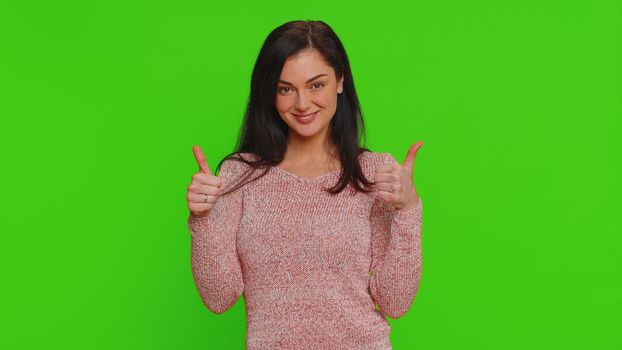 Like. Pretty woman in sweater raises thumbs up agrees with something or gives positive reply recommends advertisement likes good, approve. Young girl isolated alone on green chroma key background