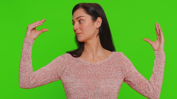 Bored pretty young woman in sweater showing blah blah gesture with hands, has not interested in the conversation, gossips, empty promises, lier. Millennial girl isolated on green chroma key background