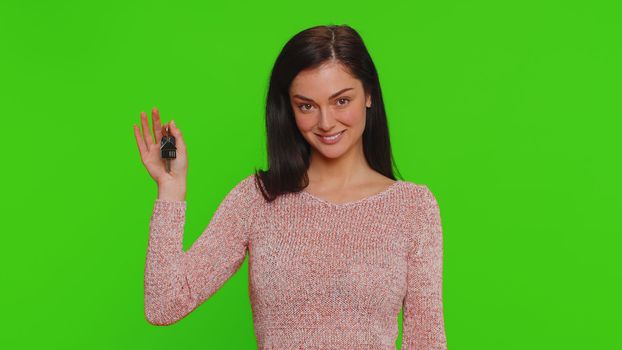 Pretty young woman in sweater real estate agent lifting hand showing the keys of new home house apartment, buying, renting property, mortgage loan. Millennial girl isolated on chroma key background