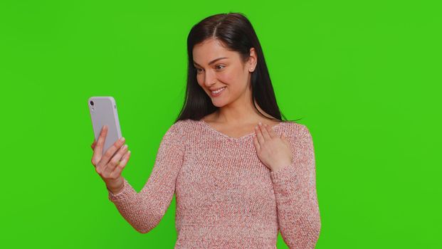 Pretty young woman influencer blogger taking selfie on smartphone, communicating video call online, recording new social media vlog story for subscribers. Girl isolated on chroma key background