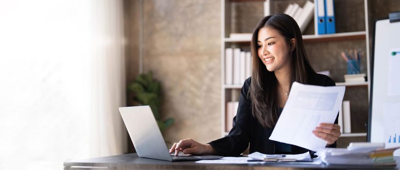 Business woman using calculator for do math finance on wooden desk in office and business working background, tax, accounting, statistics and analytic research concept...