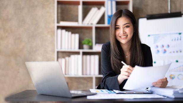 Business woman using calculator for do math finance on wooden desk in office and business working background, tax, accounting, statistics and analytic research concept...