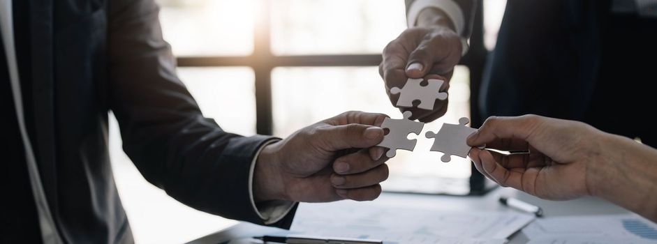 A group of business people assembling jigsaw puzzle. The concept of cooperation, teamwork, help and support in business...