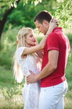 couple in love a blonde girl and a guy in a red t-shirt at a picnic in a park with green grass