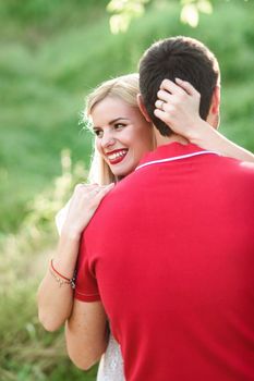 couple in love a blonde girl and a guy in a red t-shirt at a picnic in a park with green grass