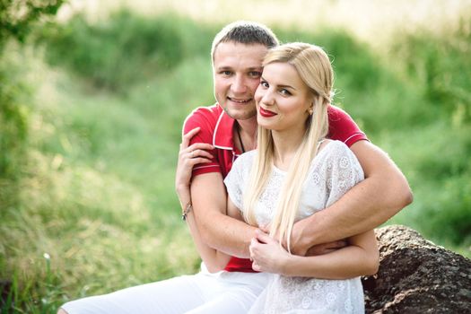 couple in love a blonde girl and a guy in a red t-shirt at a picnic in a park with green grass