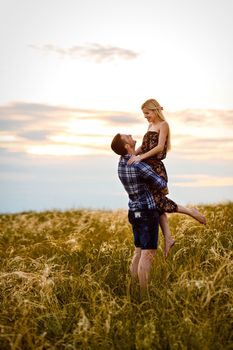 couple in love blonde girl and guy in the grass at sunset