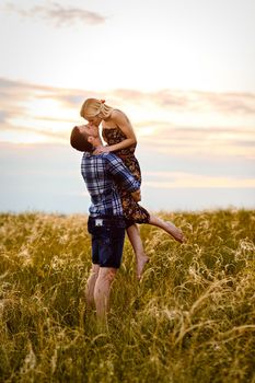 couple in love blonde girl and guy in the grass at sunset