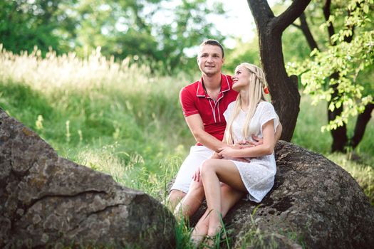 couple in love a blonde girl and a guy in a red t-shirt at a picnic in a park with green grass