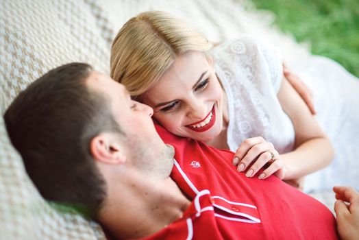 couple in love a blonde girl and a guy in a red t-shirt at a picnic in a park with green grass