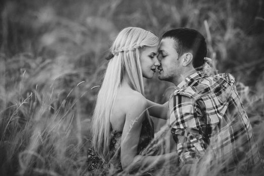 couple in love blonde girl and guy in the grass at sunset