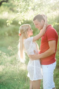 couple in love a blonde girl and a guy in a red t-shirt at a picnic in a park with green grass