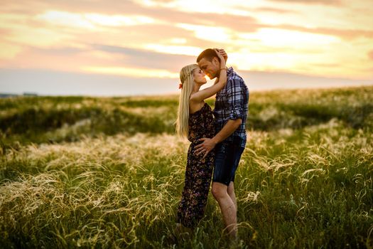 couple in love blonde girl and guy in the grass at sunset