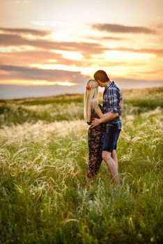 couple in love blonde girl and guy in the grass at sunset