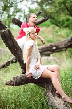 couple in love a blonde girl and a guy in a red t-shirt at a picnic in a park with green grass