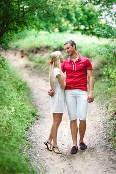 couple in love a blonde girl and a guy in a red t-shirt at a picnic in a park with green grass