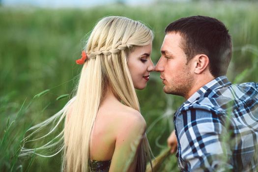 couple in love blonde girl and guy in the grass at sunset