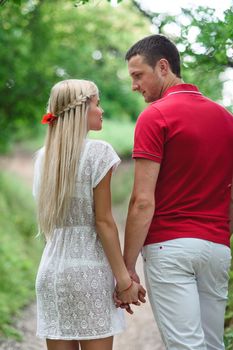 couple in love a blonde girl and a guy in a red t-shirt at a picnic in a park with green grass