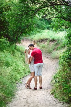 couple in love a blonde girl and a guy in a red t-shirt at a picnic in a park with green grass