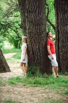 couple in love a blonde girl and a guy in a red t-shirt at a picnic in a park with green grass