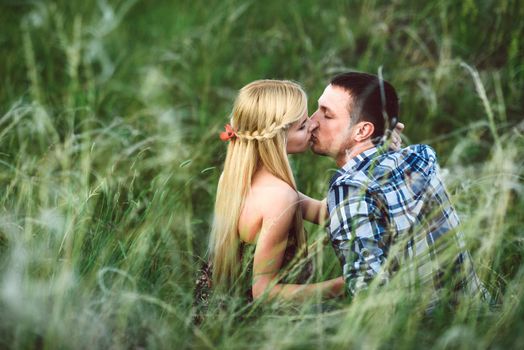 couple in love blonde girl and guy in the grass at sunset