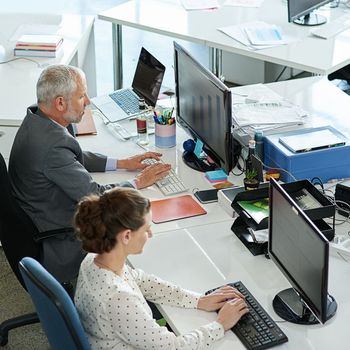 Hard at work in the office. colleagues working on their computers while sitting in an office