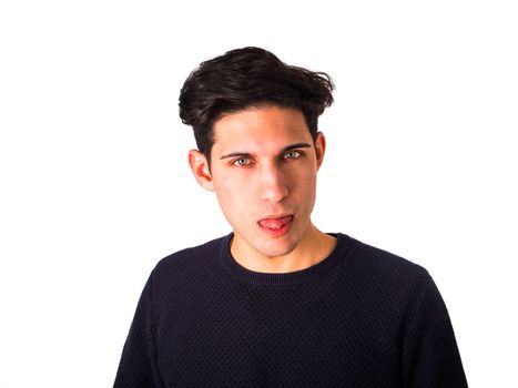 Attractive young man doing fun expression sticking out tongue, looking at camera