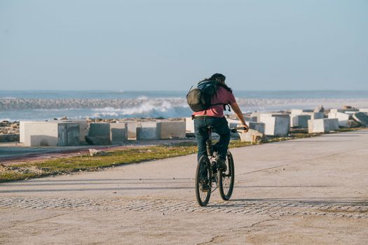 Bicycle touring along the promenade on the wavy blue sea shore.