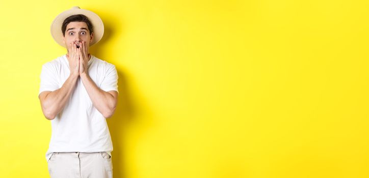 Concept of tourism and summer. Shocked guy jumping from fear, standing startled against yellow background.