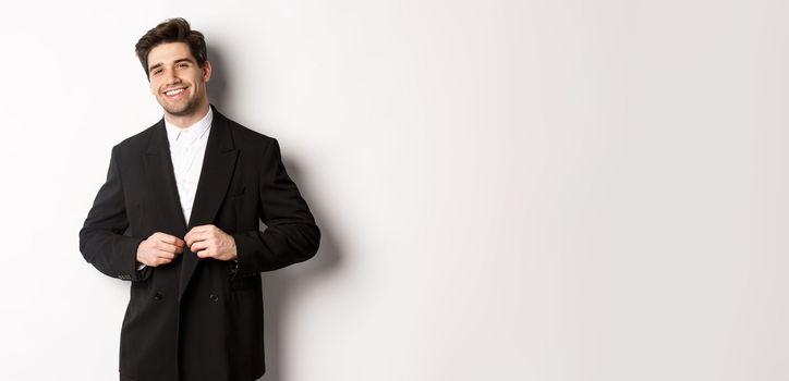 Image of handsome and confident businessman with beard, button down jacket and smiling, standing against white background.