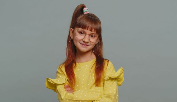 Cheerful lovely young preteen child girl kid in glasses smiling, looking at camera. Little funny female toddler children schoolgirl isolated portrait alone on studio gray background. Childhood