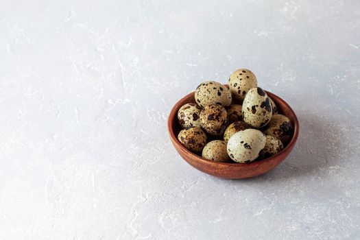 quail eggs in wooden bowl on grey concrete background, copy space, minimalism, Easter concept