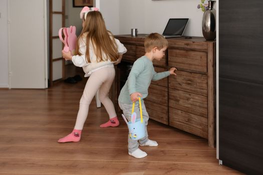 Children at home collect chocolate eggs in a basket