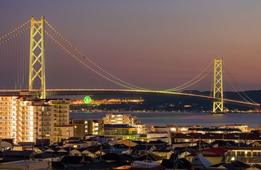 Akashi Suspension Bridge Lit with Rainbow Colors over City at Night. High quality photo