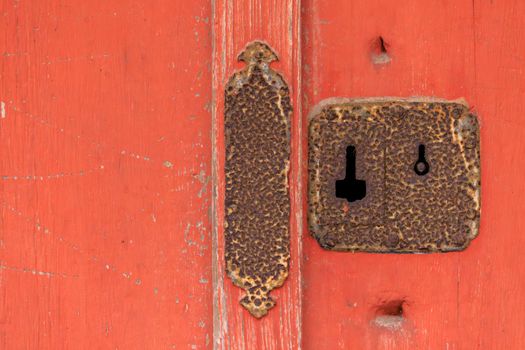 Closeup of rusted antique keyhole and lock on red wooden door. High quality photo