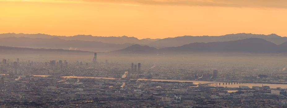 Panoramic view of haze layer over city with orange glow in sky at sunrise. High quality photo