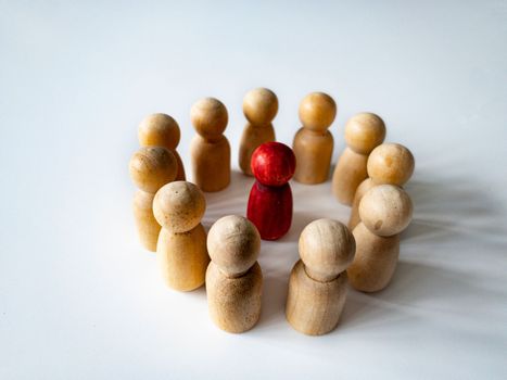 Red wooden doll figure surrounded by other doll figure on white background. Harassment and bully concept.