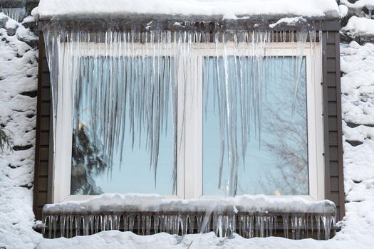 Icicles on the window of the house on a frosty day..