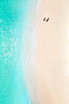 A couple walks along the Beach of Mauritius in the Indian ocean. Top view of the beach with turquoise water on the tropical island of Mauritius.Aerial photography