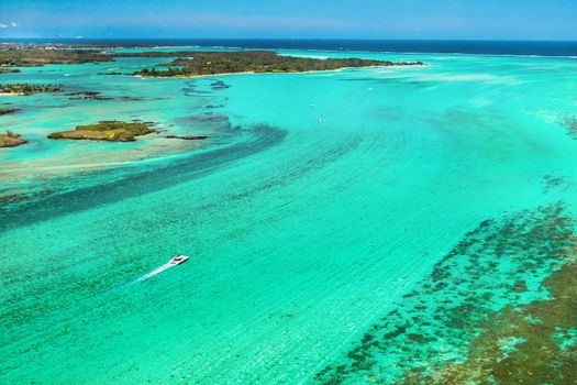 Aerial picture of the east coast of Mauritius Island. Beautiful lagoon of Mauritius Island shot from above. Boat sailing in turquoise lagoon.