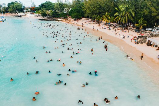 The view from the bird's eye view of the ocean, filled with people on a hot Sunny day.People swim in the Indian ocean on the island of Mauritius.