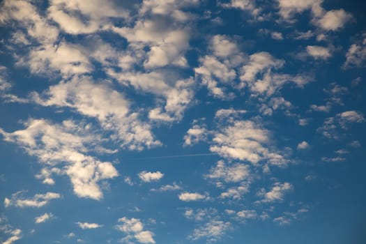 Beautiful blue sky with white fluffy clouds at sunset. Sky panorama for screensavers, postcards, calendar, presentations. Low point at wide angle. Warm spring or summer evening.