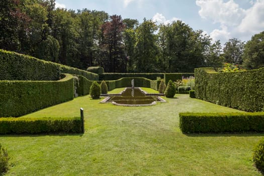 green english landscape garden made of grass boxwood and yew hedges with a statue in the background