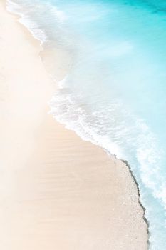 Tropical beach with a bird's eye view of the waves breaking on the tropical Golden sandy beach. Sea waves gently loop along the beautiful sandy beach