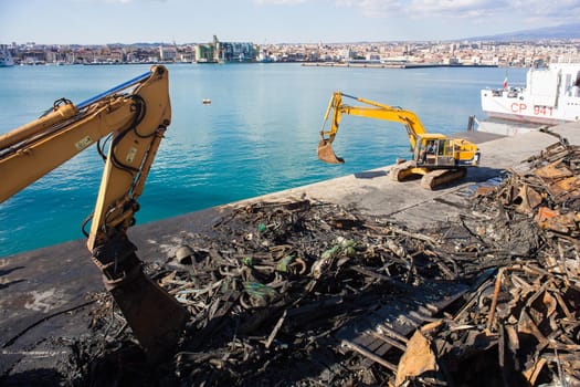 Cranes next to the piles of garbage and metal scrap in the Catania pier