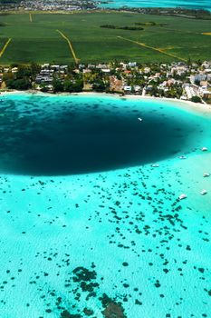 Top view of the Blue Bay lagoon of Mauritius. A boat floats on a turquoise lagoon.