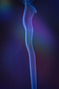 A vertical shot of smoke in colorfull backlight with a blue note