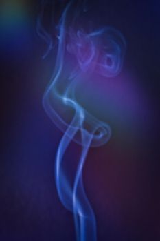 A vertical shot of smoke in colorfull backlight with a blue note