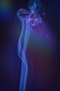 A vertical shot of smoke in colorfull backlight with a blue note