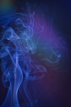 A vertical shot of smoke in colorfull backlight with a blue note